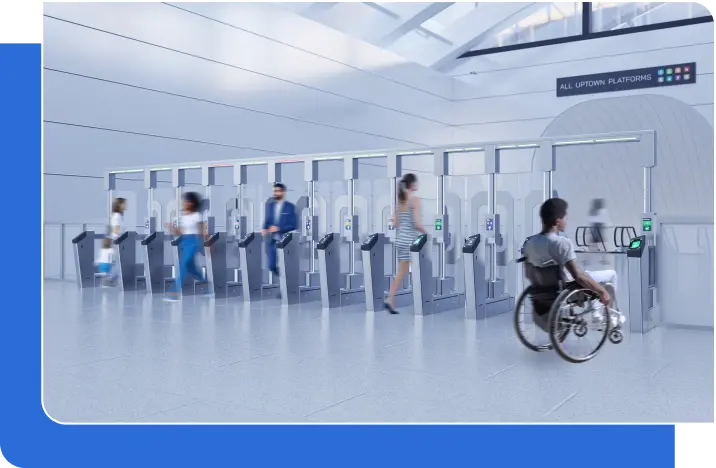 A man in a wheelchair navigates through a busy train station, showcasing accessibility with the FEnX Fare Gate.