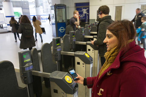 Woman tapping phone wallet on transit gate