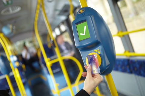 Person tapping a contactless bank card while boarding bus